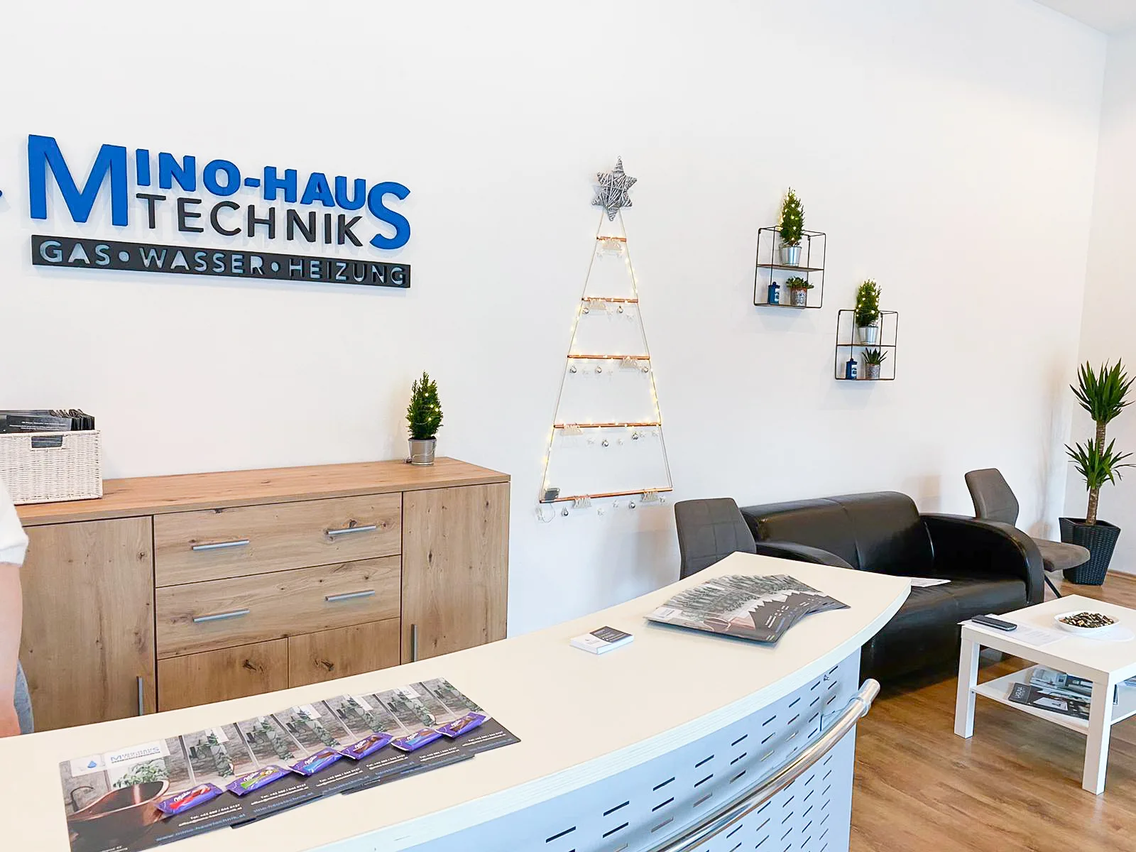 Empfangsbereich von Mino-Haustechnik mit dem Firmenlogo an der Wand und Prospekten auf dem Tresen